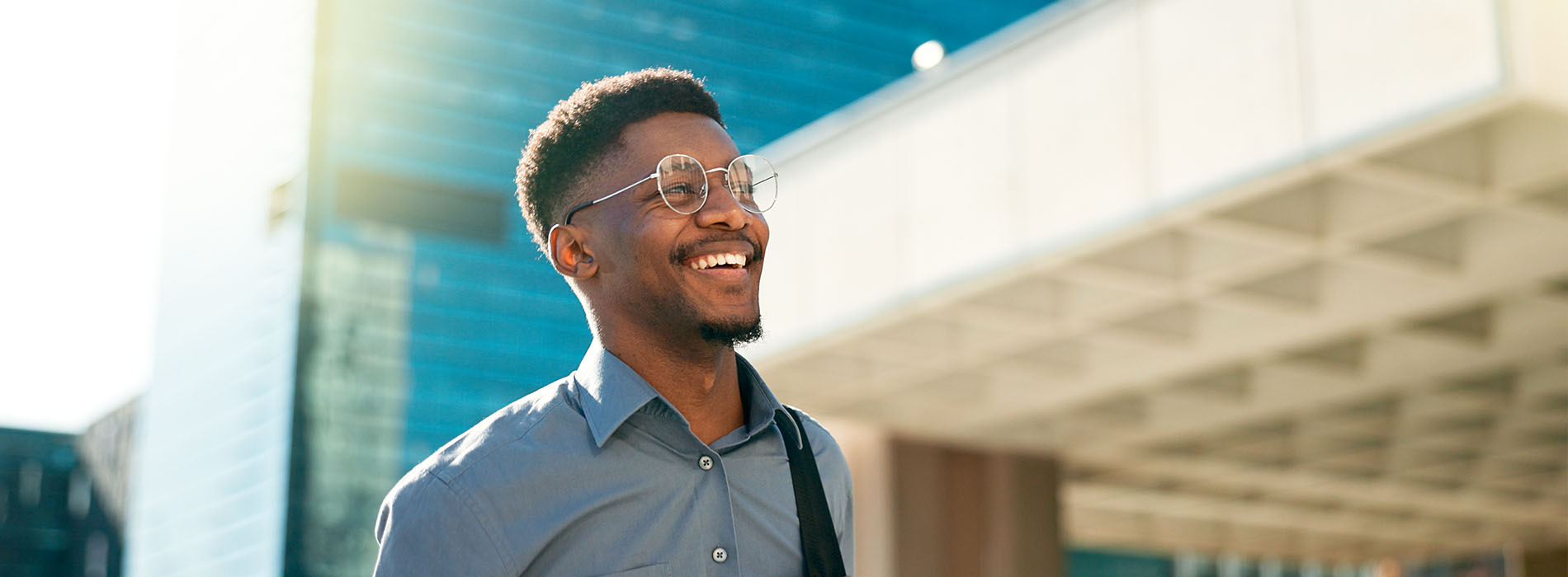 A young man in a suit smiling, standing outdoors during the day.