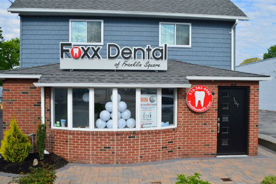 A sign for a dental practice, Fox Dental, with a red and white logo, located in a small brick building.