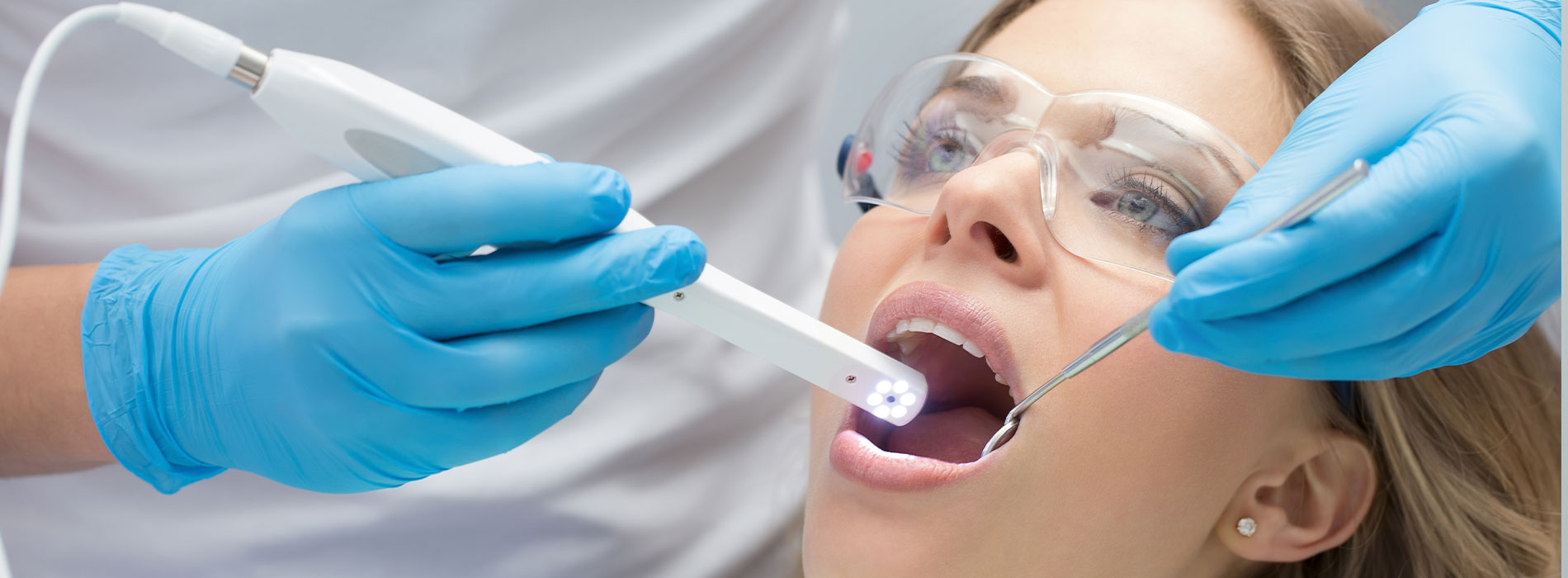 A woman receiving dental treatment, with a dentist using a dental drill and the patient wearing protective eyewear.