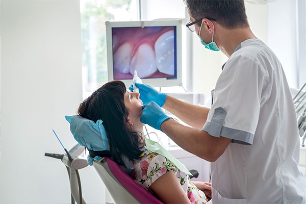 This is an image of a dental professional performing a procedure on a patient in a clinical setting.