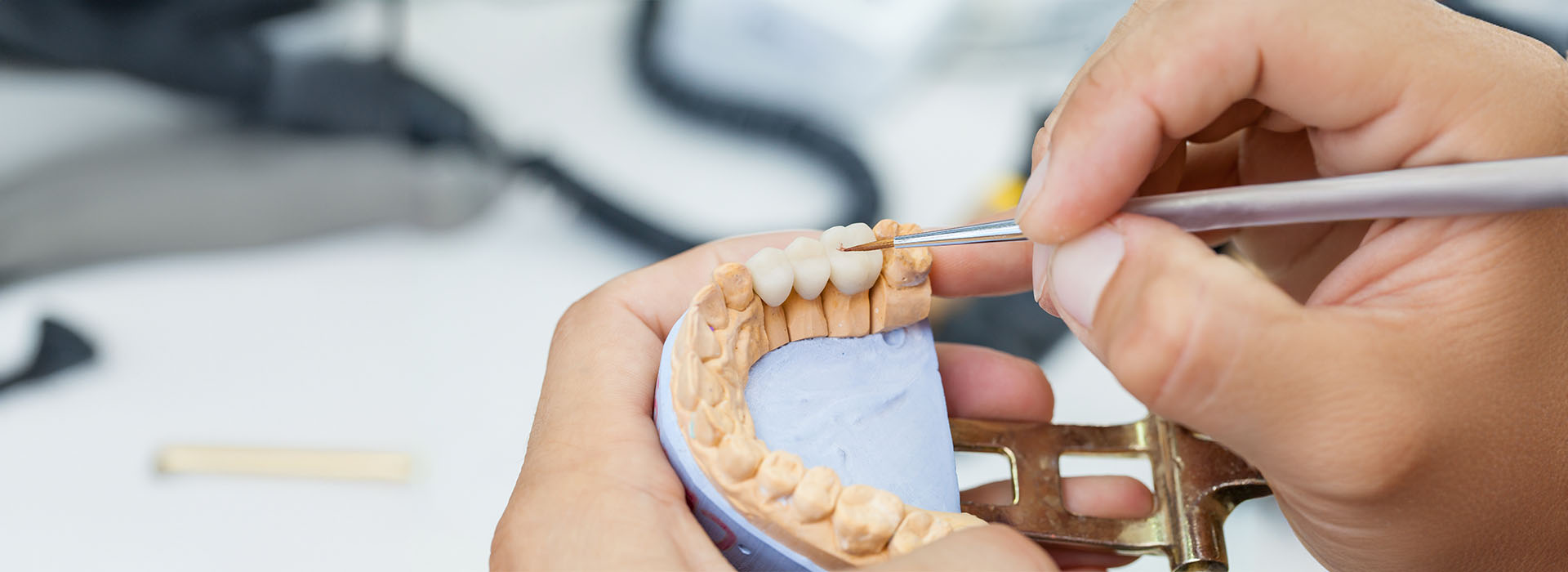 The image shows a person working on a craft or project, specifically handling a small object with their hands and using a tool to manipulate the item.