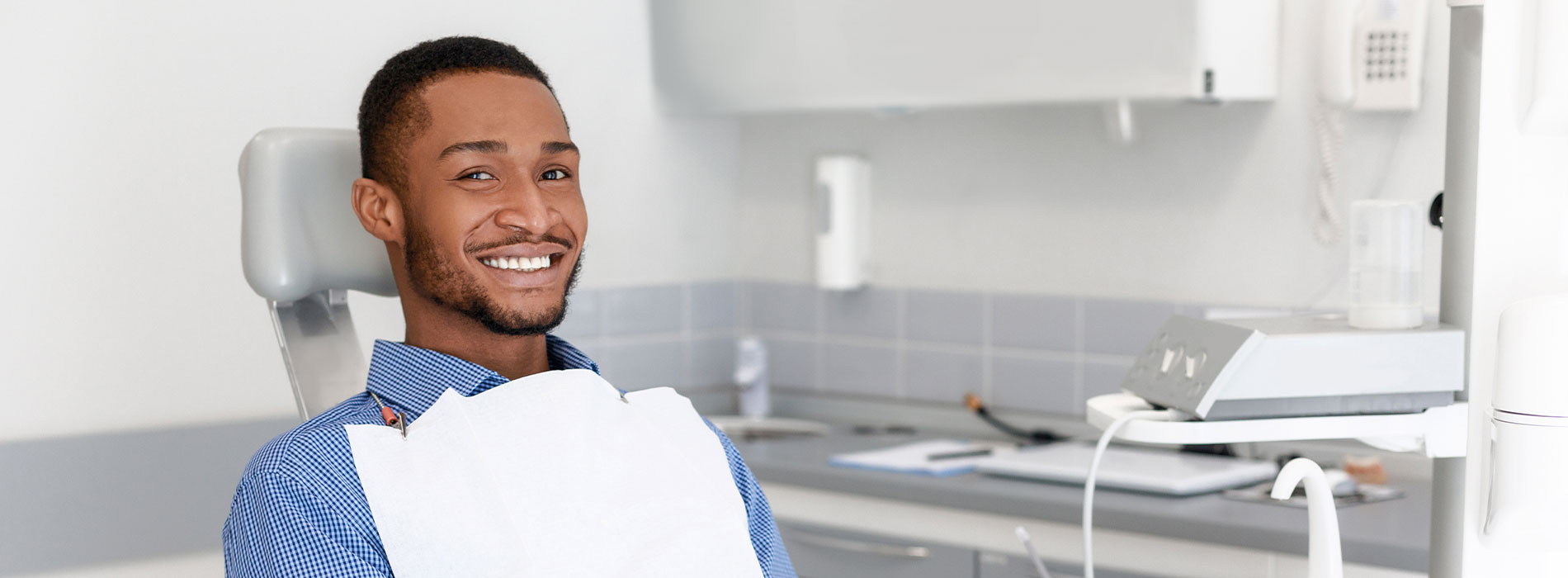 The image shows a person sitting in a dental chair, likely in a dental office setting.
