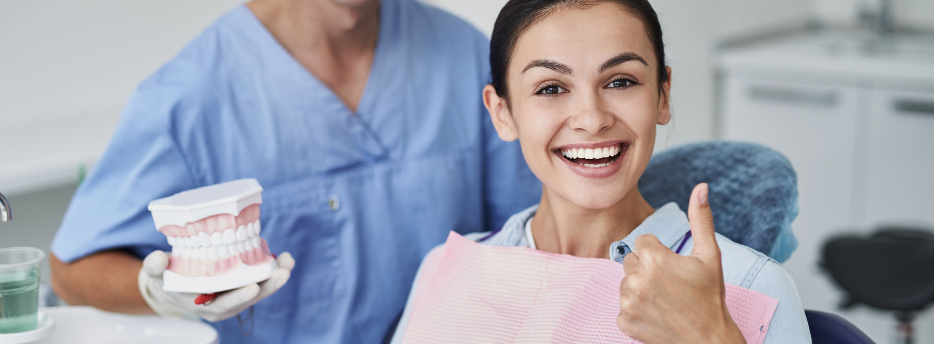 A dental hygienist and a dentist in a professional setting, smiling at the camera.