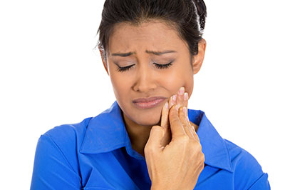 The image features a woman with her eyes closed, holding her face and looking upwards. She appears to be in distress or pain, possibly due to dental issues, as suggested by her hand placement near her mouth.