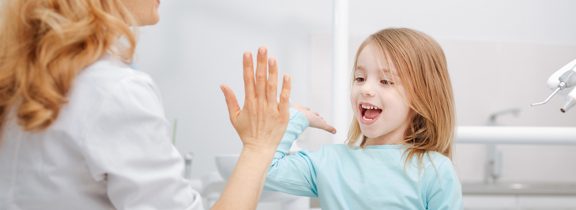The image shows a woman and a young girl in a bathroom, with the woman extending her hand towards the child who is smiling at her.