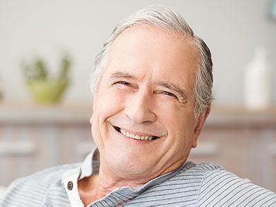 The image shows an elderly man with a smile, appearing relaxed and content.